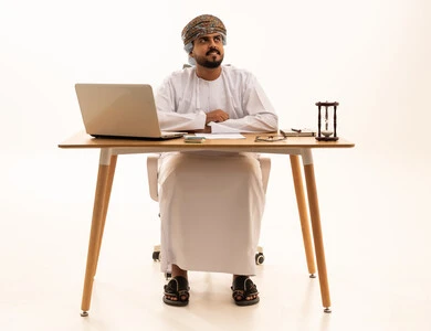 رجل أعمال عُماني في المكتب مع كمبيوتر محمول