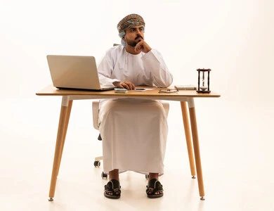 Omani Businessman at Desk with Laptop and Hourglass