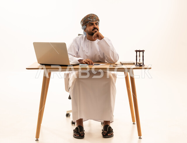 موظف عماني بالزي التقليدي يفكر خلف المكتب