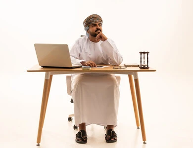 موظف عماني بالزي التقليدي يفكر خلف المكتب