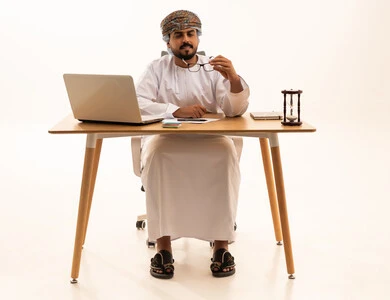 رجل أعمال عماني يعمل على مكتب مع حاسوب محمول