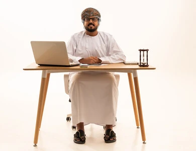 Omani Businessman at Desk with Laptop and Hourglass