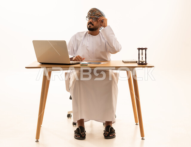 رجل عماني في المكتب مع كمبيوتر وساعة رملية