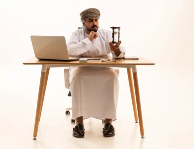 Omani Businessman at Desk with Laptop and Hourglass