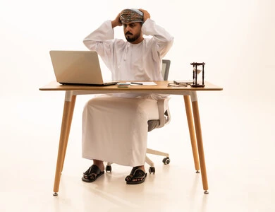 Stressed Omani Businessman with Laptop at Office Desk