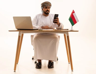 Omani Businessman with Laptop and Flag at Desk