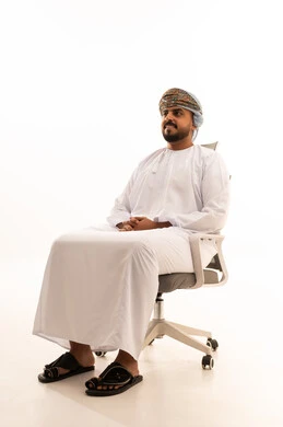 رجل عماني بالزي التقليدي يجلس على كرسي مكتب