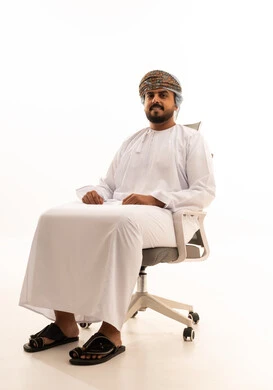رجل عماني بالزي التقليدي على كرسي مكتب