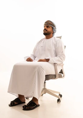 رجل عماني بالزي التقليدي يجلس على كرسي مكتب