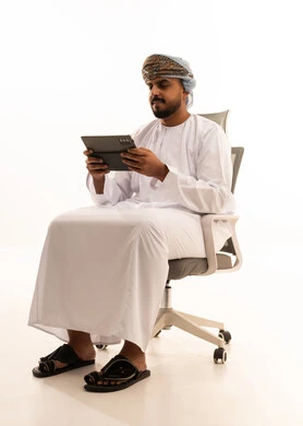 رجل عماني بالزي التقليدي يستخدم جهاز لوحي