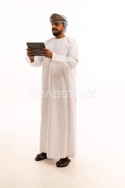 رجل عماني يستخدم جهاز لوحي بخلفية بيضاء