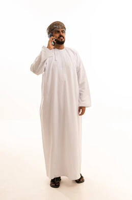 رجل عماني بالزي التقليدي يستخدم الهاتف المحمول