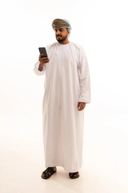 رجل عماني بالزي التقليدي يستخدم الهاتف الذكي في الاستوديو