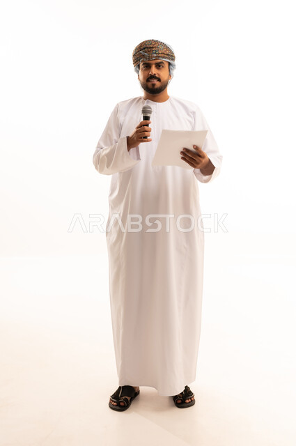 رجل عماني يحمل ميكروفون وورقة في استوديو