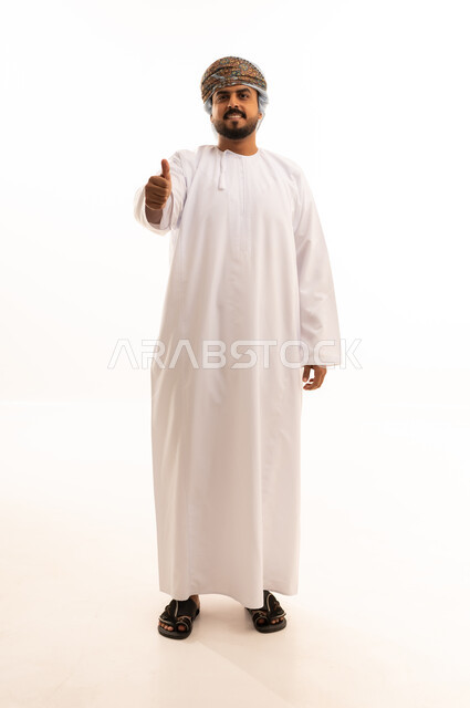 رجل عماني يرتدي الدشداشة والكمة مع إيماءة الإبهام
