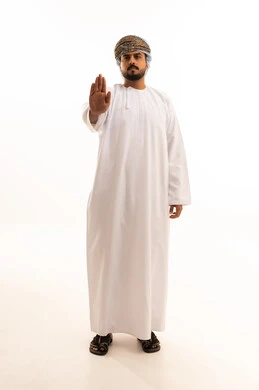 رجل عماني يرتدي الدشداشة والكمة يشير بحركة توقف