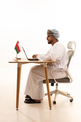 Omani Man Working on Laptop with Oman Flag