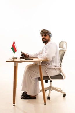 رجل أعمال عماني يجلس على مكتب مع جهاز لوحي