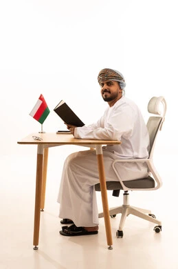رجل عُماني بالزي التقليدي على مكتب العمل