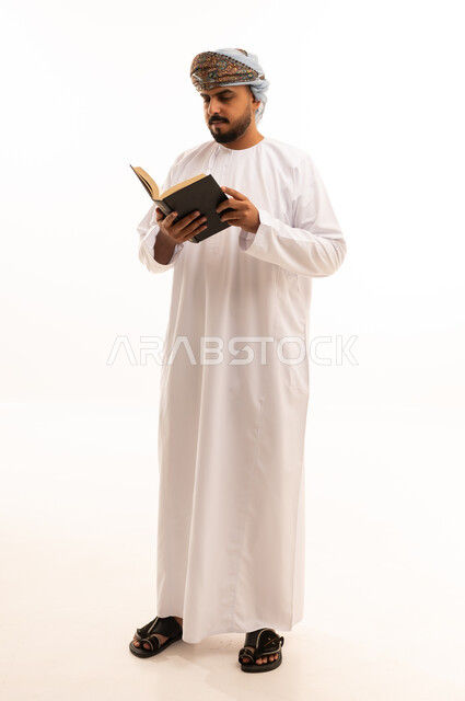 رجل عُماني يقرأ كتاباً بالزي التقليدي