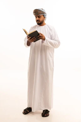 رجل عُماني يقرأ كتاباً بالزي التقليدي