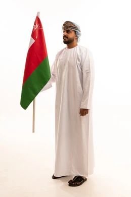 رجل عماني يحمل علم سلطنة عمان على خلفية بيضاء