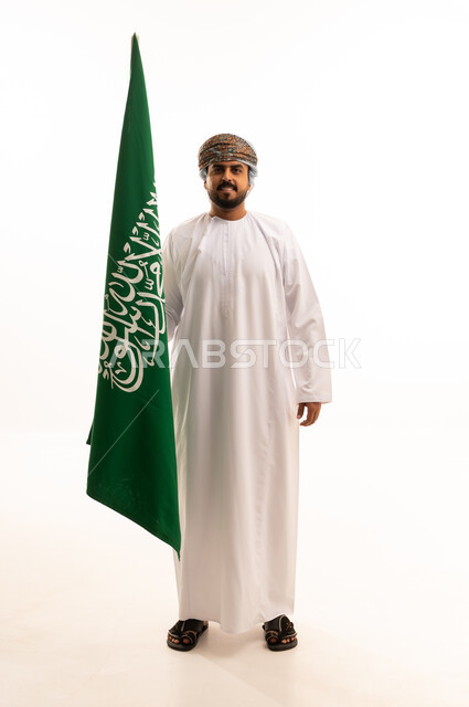 رجل عماني يحمل علم المملكة العربية السعودية بخلفية بيضاء