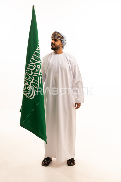 رجل عُماني يحمل علم السعودية في الاستوديو