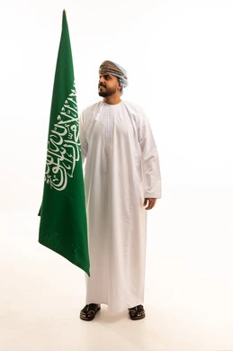 رجل عُماني يحمل علم السعودية في الاستوديو
