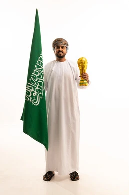 رجل عُماني بالزي التقليدي يحمل علم السعودية وكأس البطولة