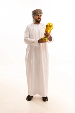 رجل عُماني بالزي التقليدي يمسك بكأس ذهبي