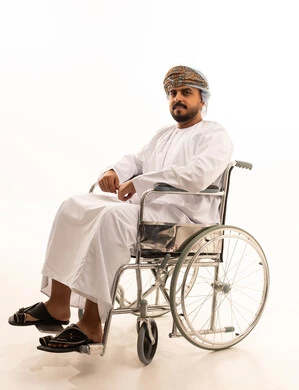 رجل عُماني على كرسي متحرك بخلفية بيضاء