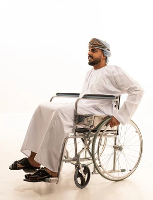 رجل عماني بالزي التقليدي على كرسي متحرك خلفية بيضاء