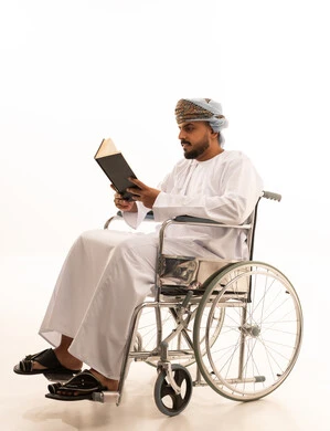 Omani Man in Wheelchair Reading Book on White Background
