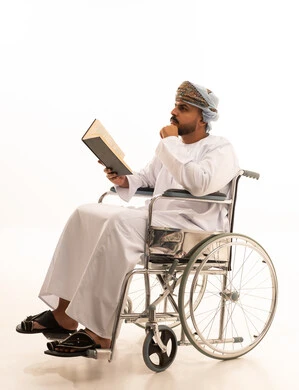 رجل عُماني على كرسي متحرك يقرأ كتاباً خلفية بيضاء