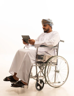 رجل عُماني على كرسي متحرك يستخدم جهاز لوحي