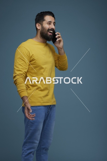 شاب سعودي يتحدث بالهاتف الذكي بملابس كاجوال صفراء