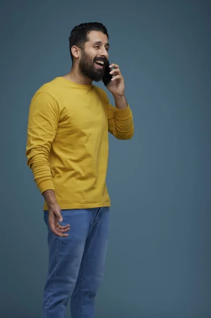 شاب سعودي يتحدث بالهاتف الذكي بملابس كاجوال صفراء