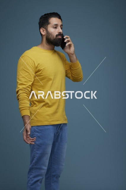 شاب سعودي يتحدث بالهاتف الذكي بملابس كاجوال صفراء
