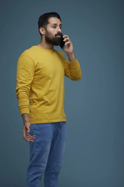 شاب سعودي يتحدث بالهاتف الذكي بملابس كاجوال صفراء