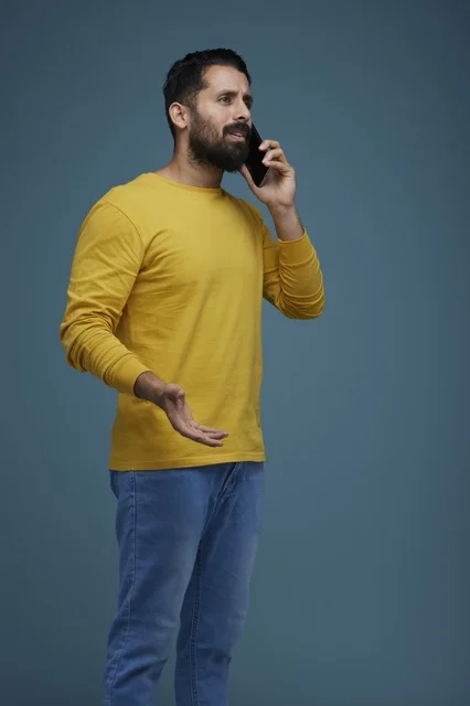 شاب سعودي يتحدث بالهاتف الذكي بملابس كاجوال صفراء