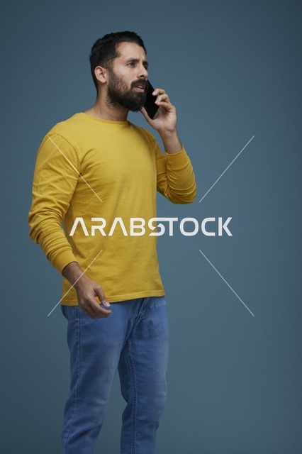شاب سعودي يتحدث بالهاتف الذكي بملابس كاجوال صفراء