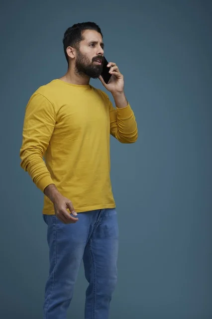 شاب سعودي يتحدث بالهاتف الذكي بملابس كاجوال صفراء