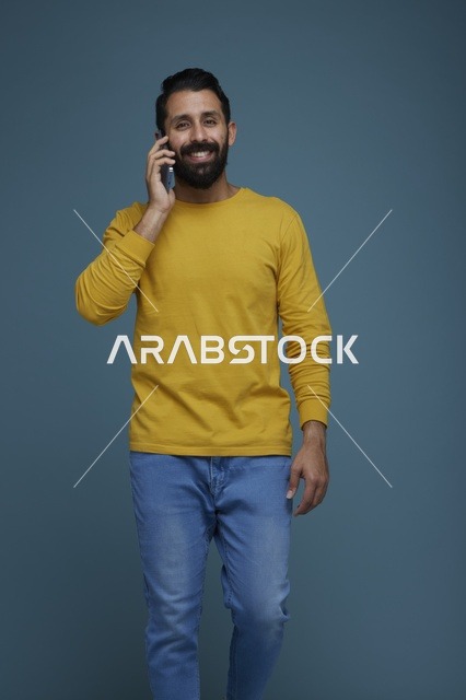 شاب سعودي يتحدث بالهاتف الذكي بملابس كاجوال صفراء