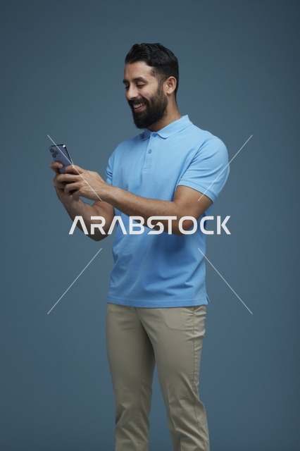شاب سعودي يستخدم الهاتف الذكي أمام خلفية زرقاء
