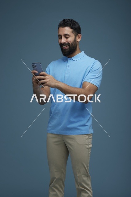 شاب سعودي يستخدم الهاتف الذكي في استوديو بملابس كاجوال