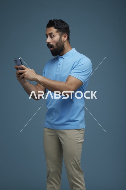 شاب سعودي متفاجئ يستخدم الهاتف الذكي بملابس كاجوال