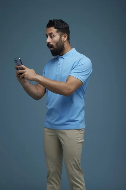 شاب سعودي متفاجئ يستخدم الهاتف الذكي بملابس كاجوال