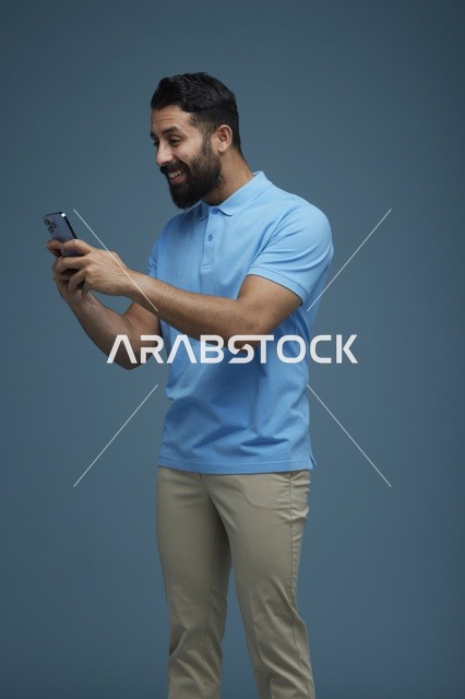 شاب سعودي يستخدم الهاتف الذكي بملابس كاجوال في استوديو