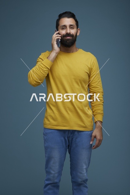 شاب سعودي يتحدث بالهاتف الذكي بملابس كاجوال